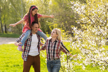 Naklejka na ściany i meble Happy family spending good time together in spring in a flowering garden