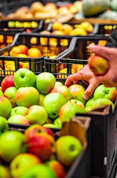 man hand holding apple in grocery store in supermarket