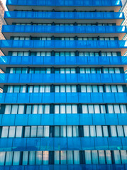 Fototapeta na wymiar Close-up view from a drone of a modern multi-storey building with many windows and balconies. Multi-storey blue glass building, apartments, hotel. Vertical photo