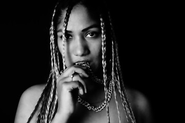 Female rapper biting chain in front of black background