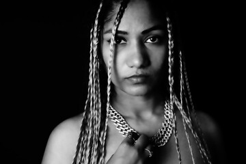 Female rapper wearing braids in front of black background - obrazy, fototapety, plakaty