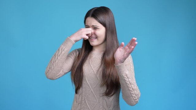 Teen kid close nose avoid horrible stench isolated blue color background