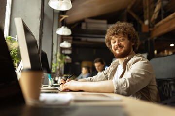 Fototapeta premium Senior developer. Happy man looking at camera and smilling. Work in modern loft style office using devices and gadgets during job processing.
