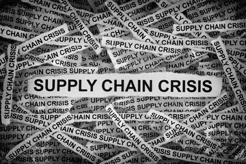 Strips of newspaper with the words Supply Chain Crisis. Black and white. Close up.