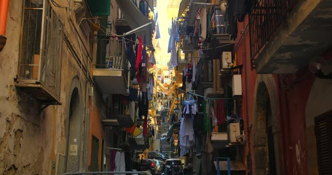 Tilt up shot of a congested narrow alley of Naples in Italy with old residential buildings on both sides on the narrow path at daytime. Old spanish district