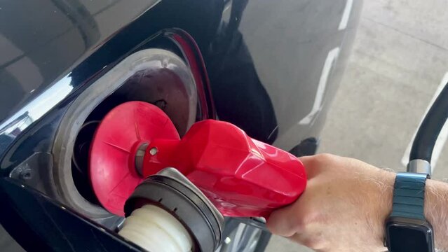 Close-up of male hand refueling a black car with expensive gas oil prices