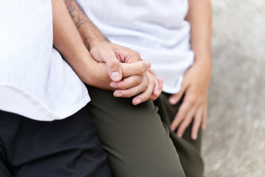 Cropped photo of two gay men holding a hand outdoors
