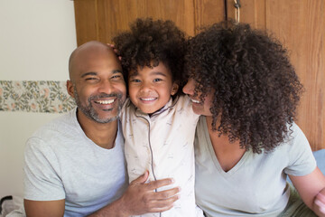 Happy parents sitting with daughter on bed