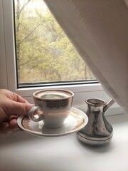 A cup of hot espresso coffee and a cezve on the windowsill in the morning. Gentle colors. arabica, aroma, backdrop