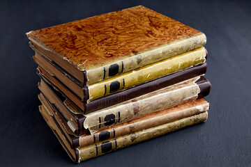 Stack of vintage dilapidated books on a dark concrete table
