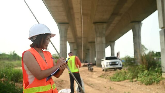 An Asian female engineer works at a motorway bridge construction site,Civil worker inspecting work on crossing construction
