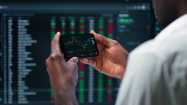Cropped shot of male stock market broker analyzing graphs on smartphone  - Powered by Adobe