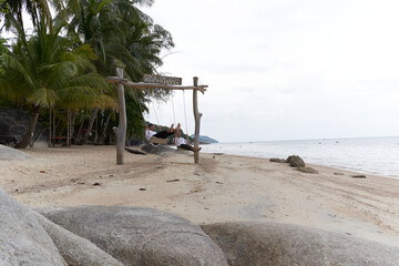 Homosexual couple swinging on a swing in the middle of a beach