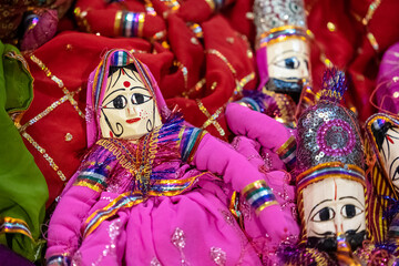 Obraz premium Handmade colorful rajasthani puppets hanging on blue colour wall for décor. Selective focus on puppet.