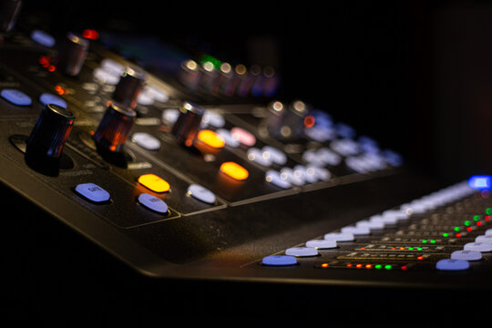 close-up ambient shoot of a modern digital audio mixing device for professional sound mixing at a concert venue in dim partial lighting with selective focus