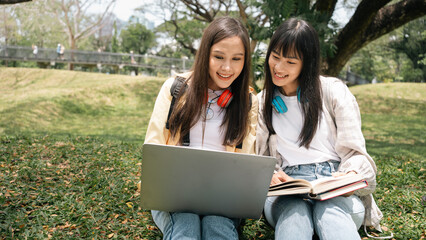 College beautiful Asian high school Portrait of diversity woman student holding books and using laptop at natural outdoors with friends at park.Prepare for college and university concept.laptop tablet