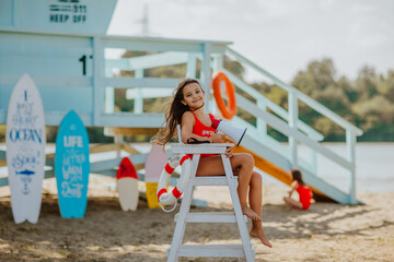 Girl in red bikini posing with megaphone sitting on summer chair at the beach