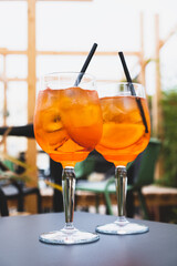 Two glasses of Aperol Spritz served on the terrace of modern bar. Popular Italian wine based cocktail and summer aperitif refreshing drink prepared with prosecco wine, bitter liqueur and soda water.