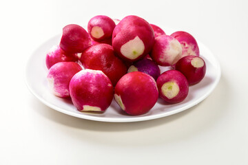 Red fresh radish in a white plate on a white table
