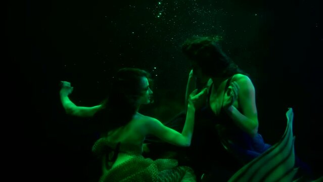 two sexy women are swimming in big aquarium or pool, mermaid and water-nymph flirting and seducing