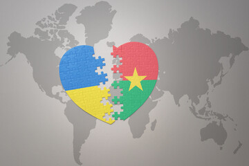 puzzle heart with the national flag of ukraine and burkina faso on a world map background. Concept.