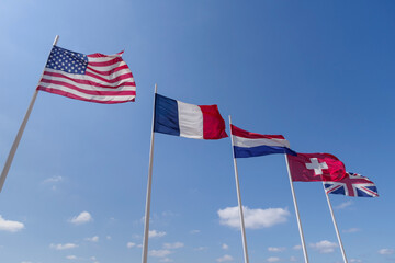 Low angle view of National flags waving against sky