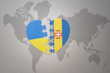 puzzle heart with the national flag of ukraine and madeira on a world map background. Concept.