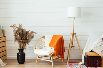 Rattan armchair, floor lamp and large vase with pampas grass in living room interior. Cozy interior...