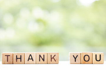 Thank you - word is written on wooden cubes on a green summer background. Close-up of wooden...