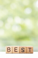Best - word is written on wooden cubes on a green summer background. Close-up of wooden elements.