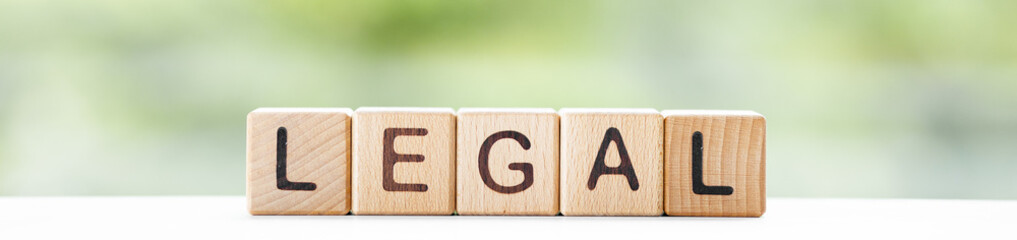 Legal - word is written on wooden cubes on a green summer background. Close-up of wooden elements.
