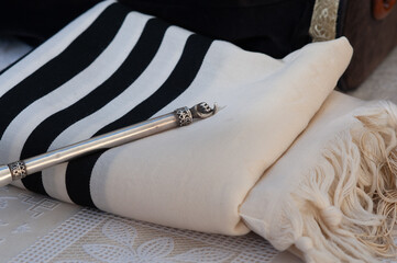 A silver pointer or yad used to guide the person reading from the Torah resting on a tallit Jewish...