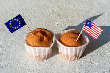 Homemade muffins with USA and EU flags on white background, copy space. The concept of cooperation between countries. The concept of trade relations between countries - obrazy, fototapety, plakaty