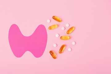Top view of paper thyroid gland with gelatin capsules and tablets.World thyroid day concept.