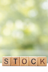 Stock - word is written on wooden cubes on a green summer background. Close-up of wooden elements.