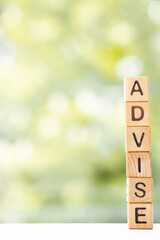 Advice - word is written on wooden cubes on a green summer background. Close-up of wooden elements.