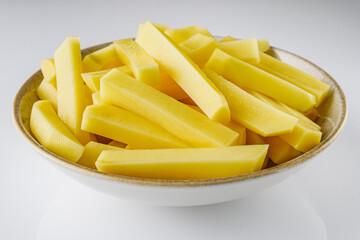 peeled potatoes sliced for french fries on a white background