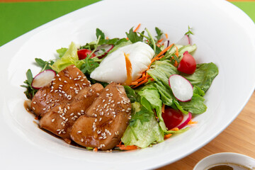 Salad with meat and poached egg in a plate.