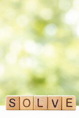 Solve - word is written on wooden cubes on a green summer background. Close-up of wooden elements.