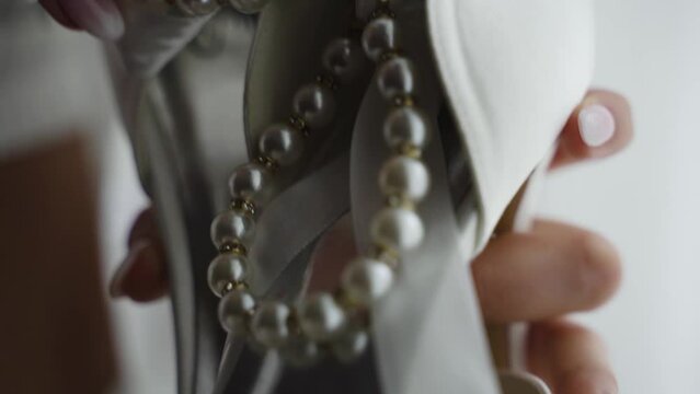 Bride touches the beads on her high-heeled wedding shoes