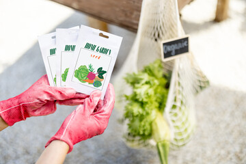 Holding vegetable seeds in paper packets with vegetables in bag on background, close-up. Growing...