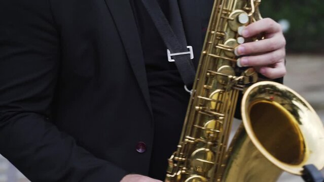 Musician in black jacket plays the golden saxophone 