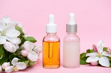 Fototapeta na wymiar Non-brand bottles of serum and facial oil on a pink background. Cosmetic set for home skin care.