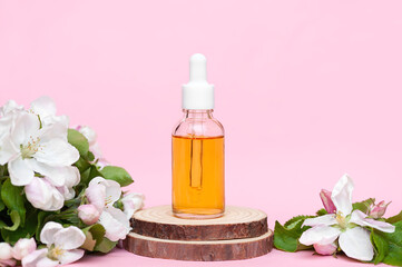 Unbranded face oil bottle on pink background and wooden podiums, mockup