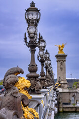Fototapeta na wymiar The ornate statues and candelabras of the famous Pont Alevmxandre III above the Seine River in the downtown of Paris, France 