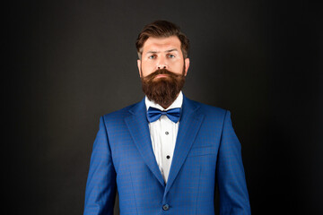 serious man in blue tuxedo bow tie. man in formalwear on black background. male formal fashion