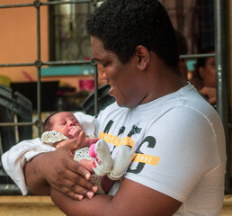 Padre sosteniendo a su bebe mientras la mira con amor