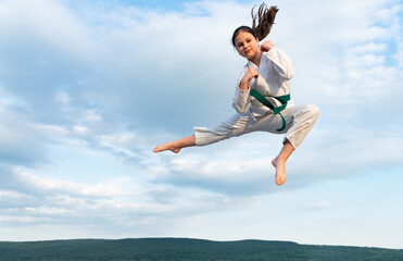 karate girl in kimono jump on sky background