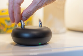hearing aid held with two fingers while  placing to charge