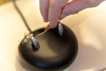 hearing aid held with two fingers while  placing to charge
